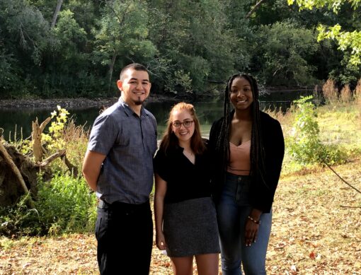 Three students standing together in front of a lake in Dayton